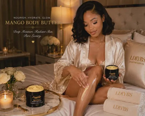 Woman applying mango body butter on a bed with candles and books in the background
